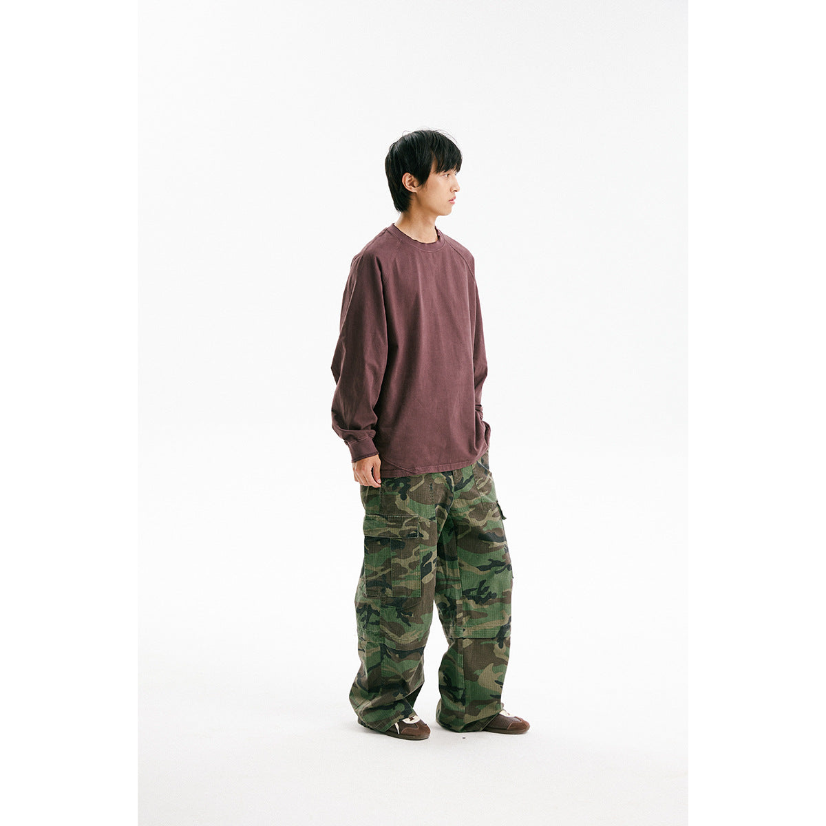 Model in profile wearing a muted plum long-sleeve shirt and green camouflage cargo pants.