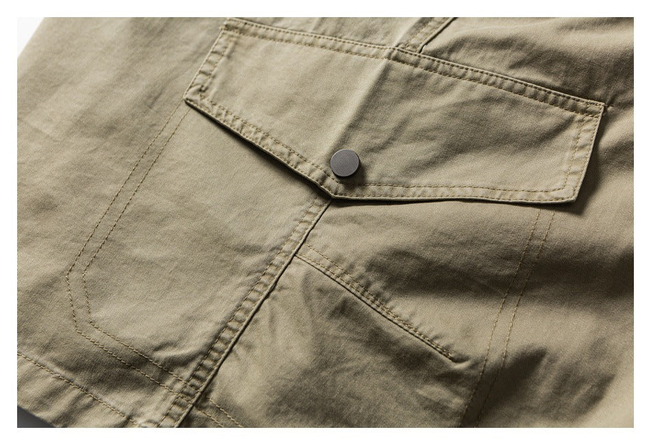 Close-up of a khaki garment with a buttoned flap pocket and visible stitching.