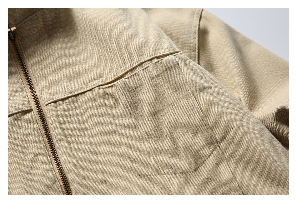 Close-up of a beige textured jacket showing a front pocket seam and bronze zipper.