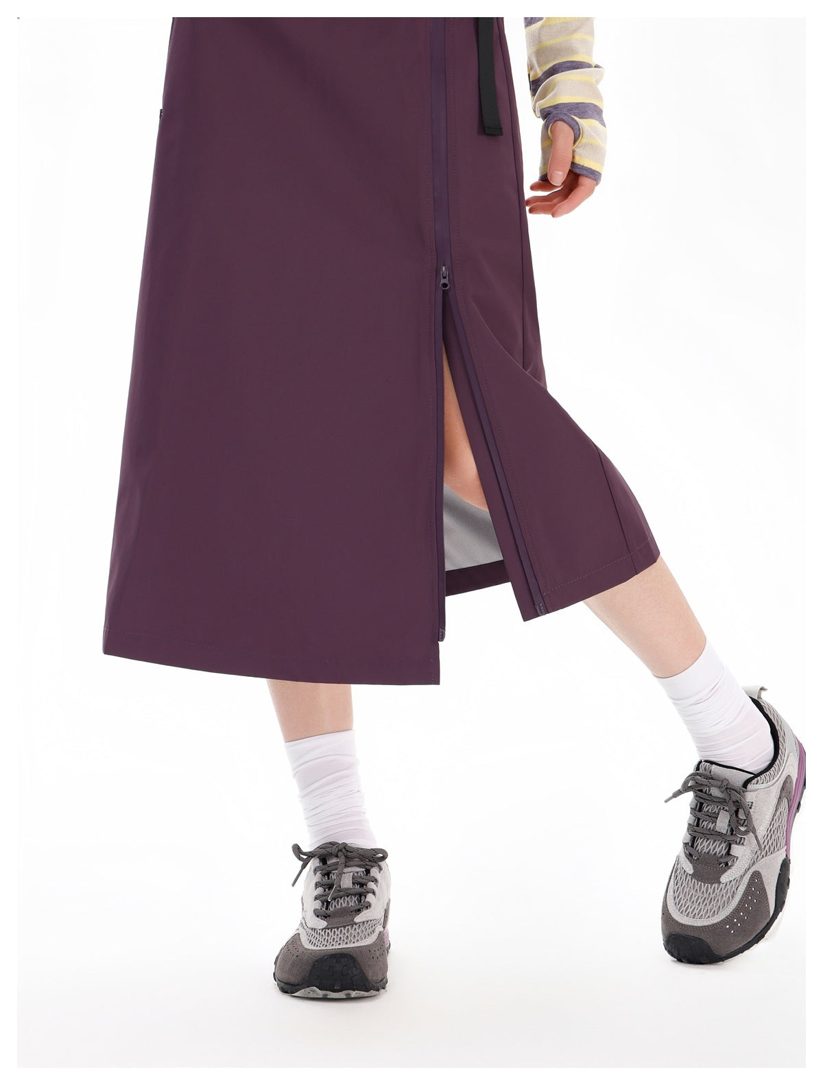 Close-up of a plum skirt's partly unzipped side slit as worn by a model.