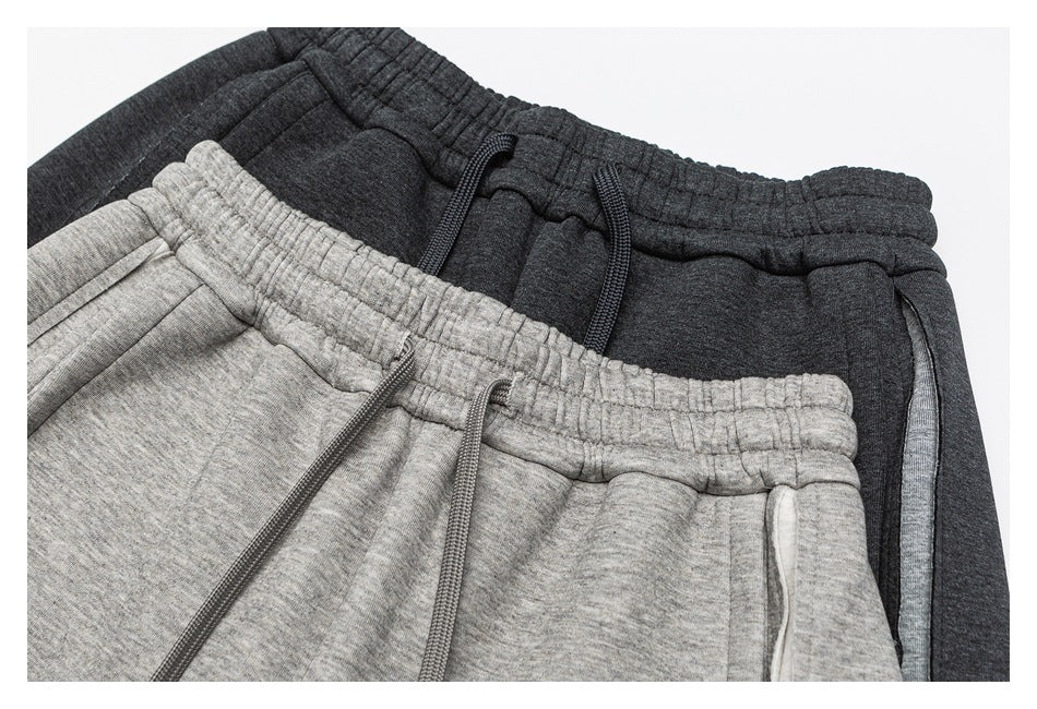 Close-up of charcoal and light gray sweatpants showing elastic waistbands, drawstrings, and pockets.