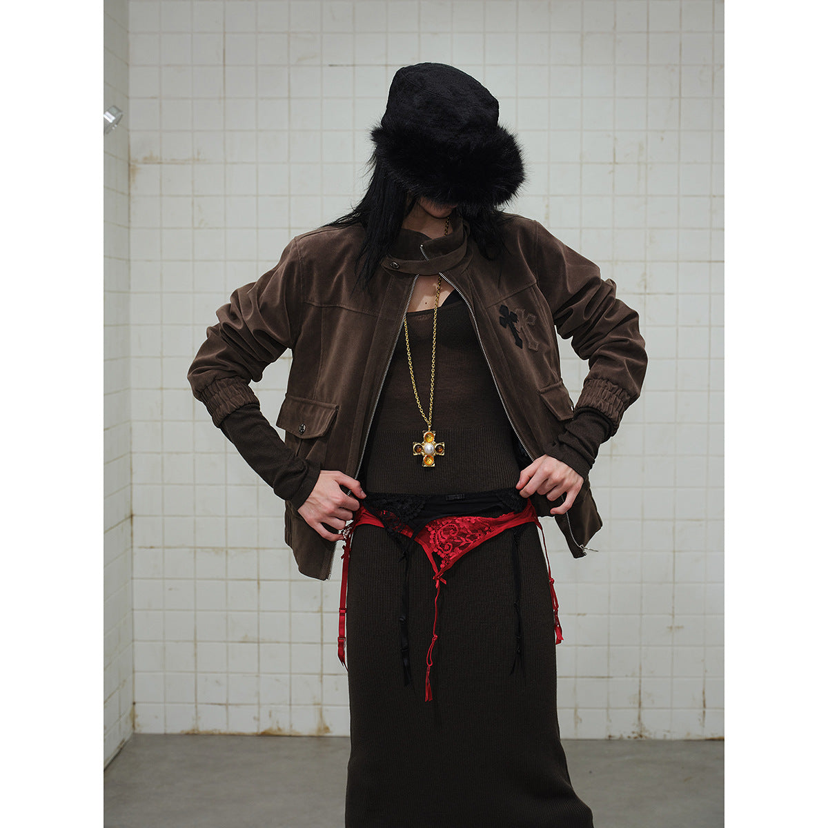 Closer view of the dark brown jacket’s raised collar, zipper, flap pockets, gathered cuffs, and chest motif.