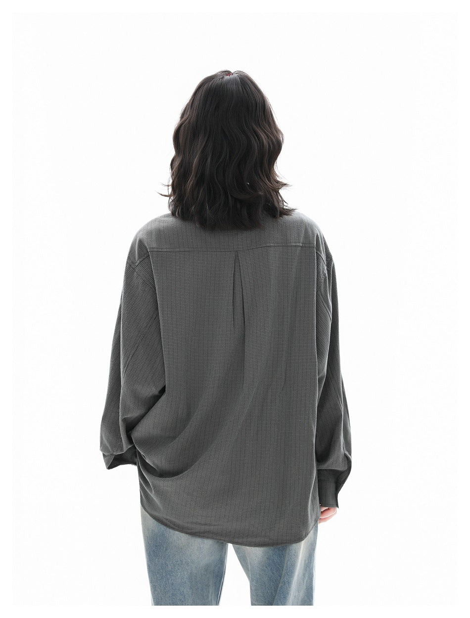 Back view of a model wearing an oversized charcoal gray shirt with a yoke seam and center pleat.