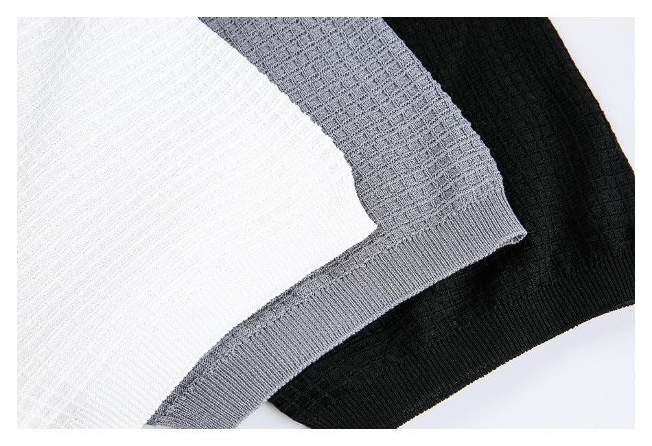 Close-up of white, gray, and black knit shirt hems, showing ribbed bands and textured fabric.