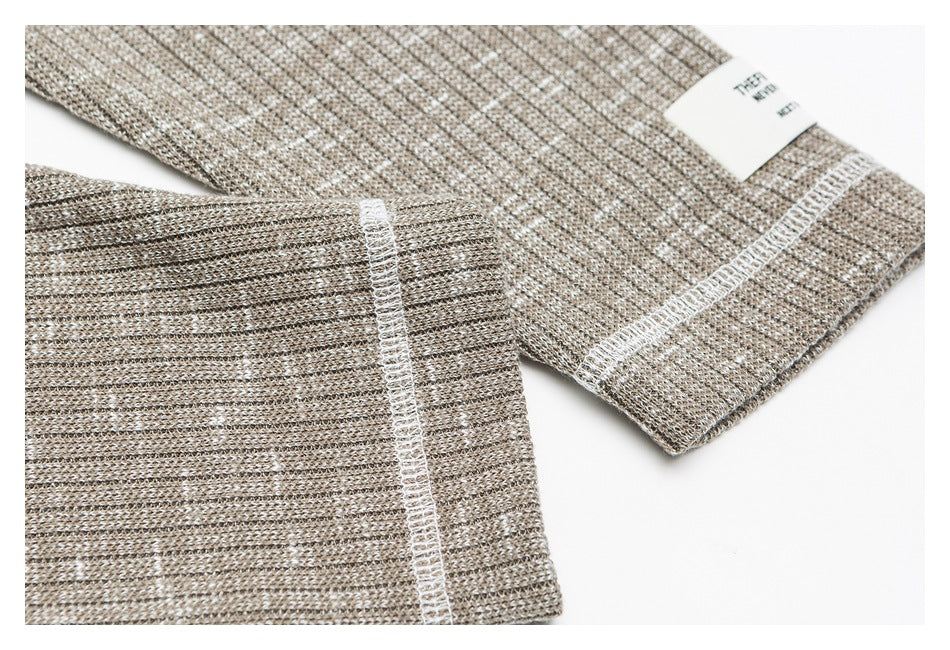 Close-up of taupe marled shirt sleeve cuffs and white overlock stitching.