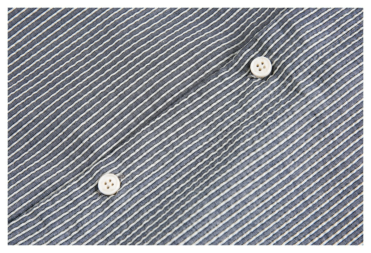 Close-up of navy, gray, and white striped shirt fabric with two ivory buttons.