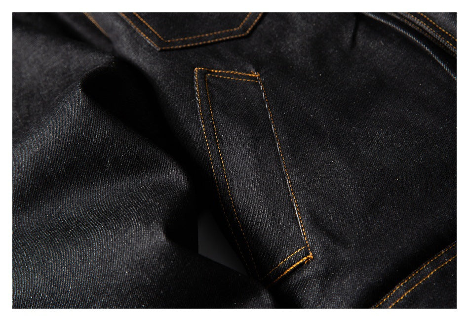 Close-up of a narrow stitched tab on black denim, with contrasting golden-brown seams.