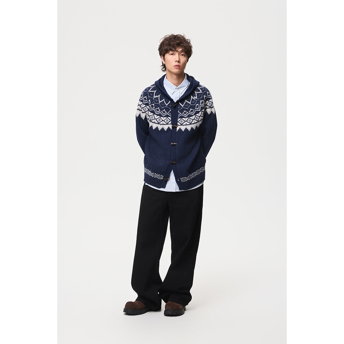 Model wearing a navy hooded cardigan with cream geometric bands and toggle closures, shown from the front.