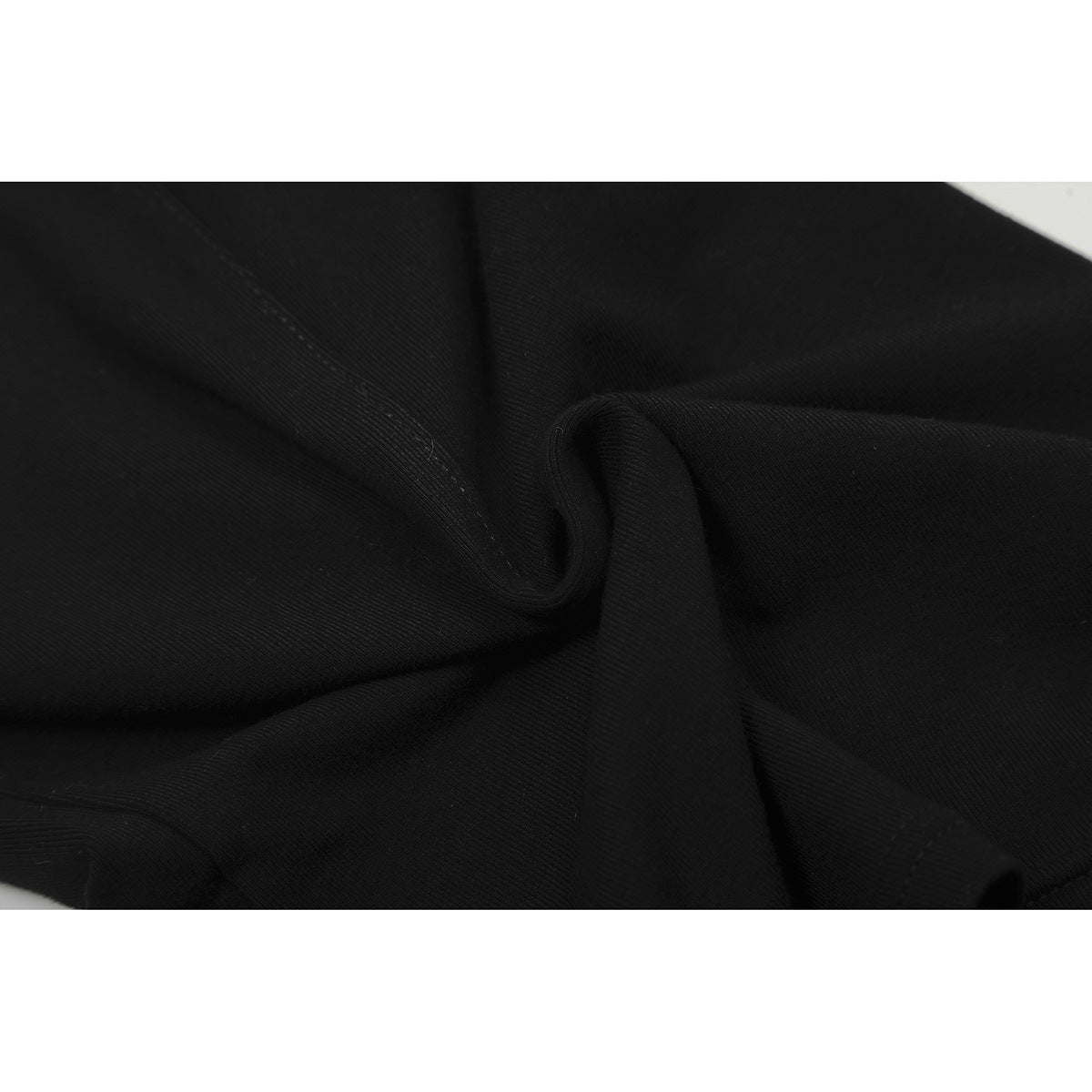 Close-up of black garment fabric arranged in folds, showing a stitched seam.