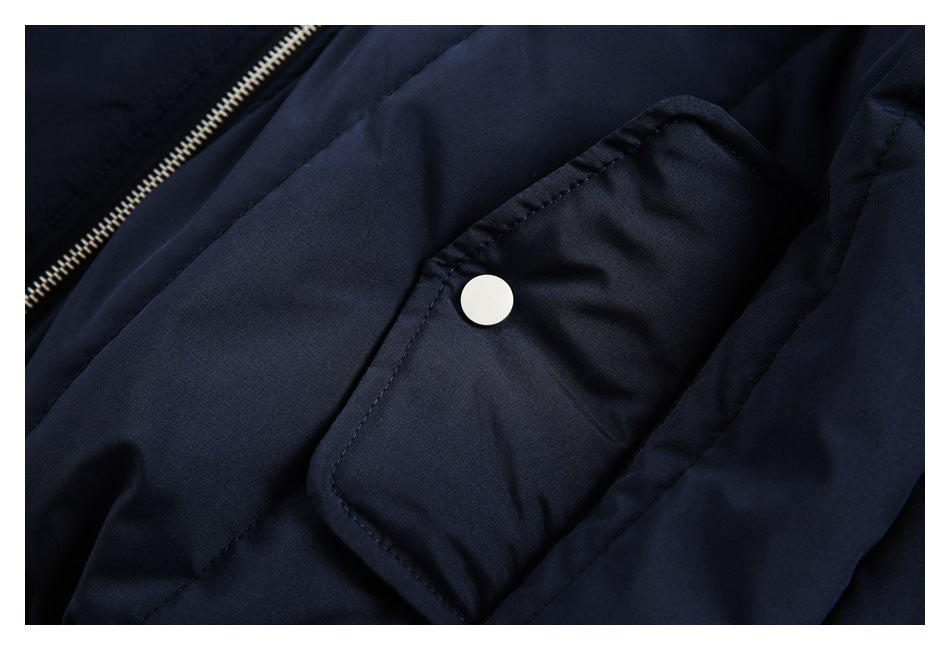 Close-up of a flap pocket with a white snap on the navy jacket, beside part of the zipper.