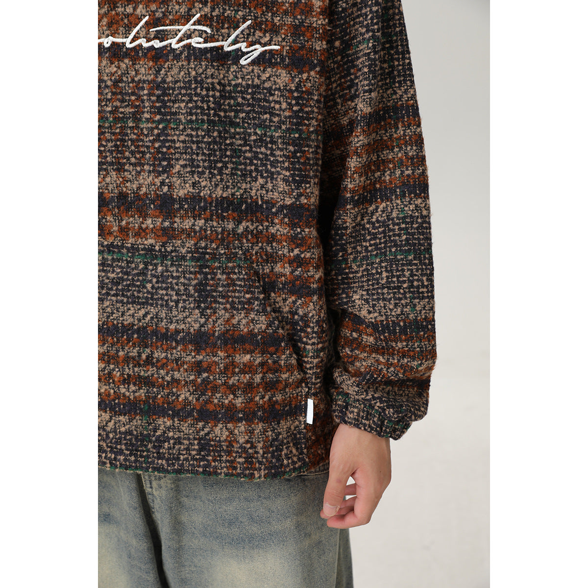 Close-up of the pullover’s multicolored striped pattern, long sleeve, cuff and hem, with part of the white chest graphic