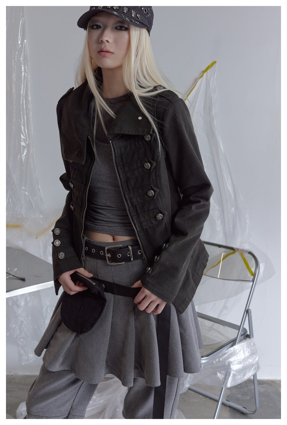 A model wears an open black button-detail jacket over a gray top and layered gray bottoms.