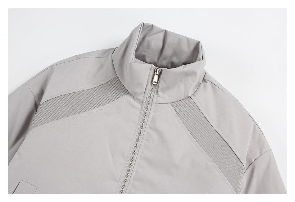 Close-up of the light gray jacket's stand collar, front zipper and ribbed shoulder panels.