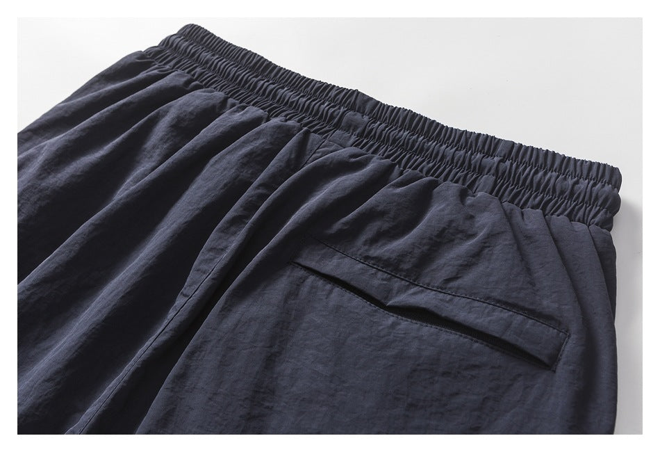 Close-up of the elastic waistband and rear zip pocket on the dark navy pants.
