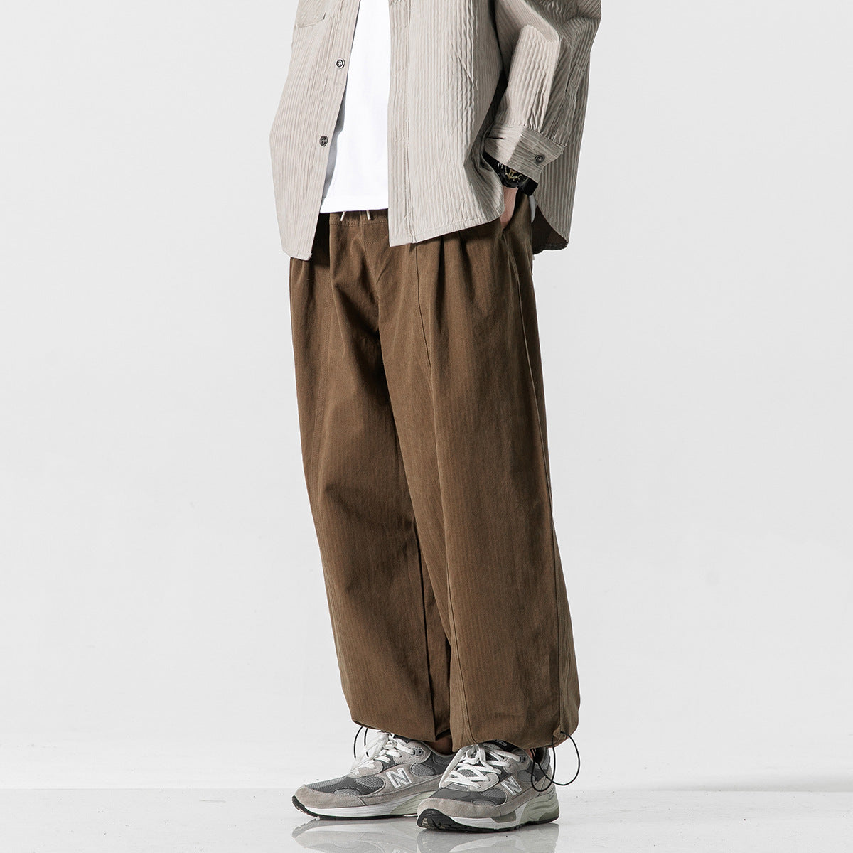 Cropped model wearing brown wide-leg pants with a loose fit and adjustable hems.