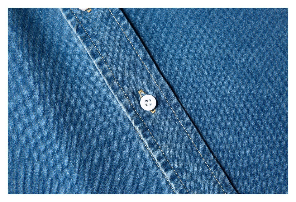 Close-up of a white button and tan topstitching on a blue denim shirt placket.