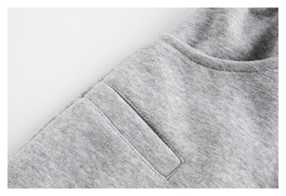 Close-up of a pocket opening and stitched panel on light gray heather sweatpants.