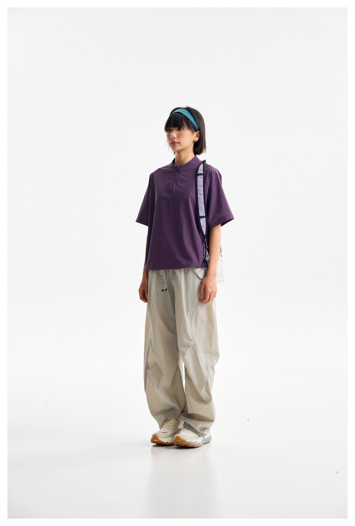 Model wearing a dark plum short-sleeve pullover with a stand collar and short front zipper.