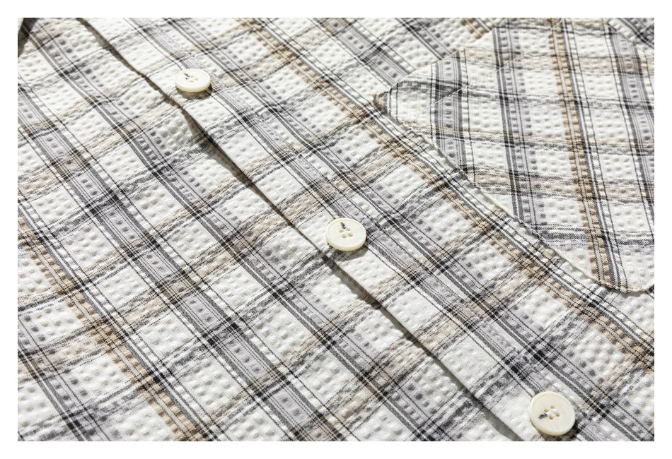 Close-up of the cream plaid shirt's button-front placket and chest pocket.