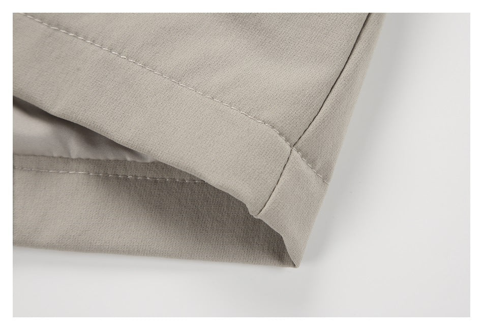 Close-up of a light taupe garment's folded edge and double-stitched seam.