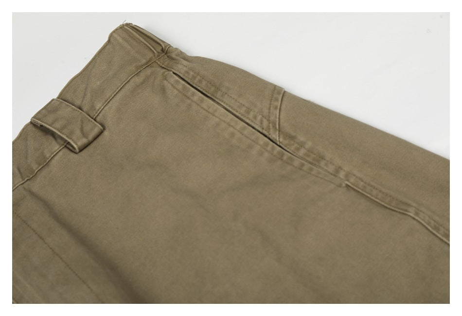 Close-up of a taupe trouser pocket opening, belt loop and stitched seams.