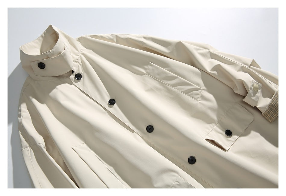 Close-up of the ivory coat showing its collar, black buttons, front pocket details, and plaid cuff lining.