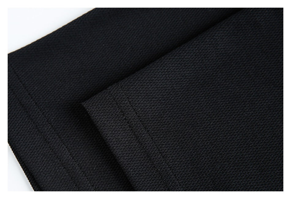 Close-up of overlapping black textured fabric showing a seam and folded edge.