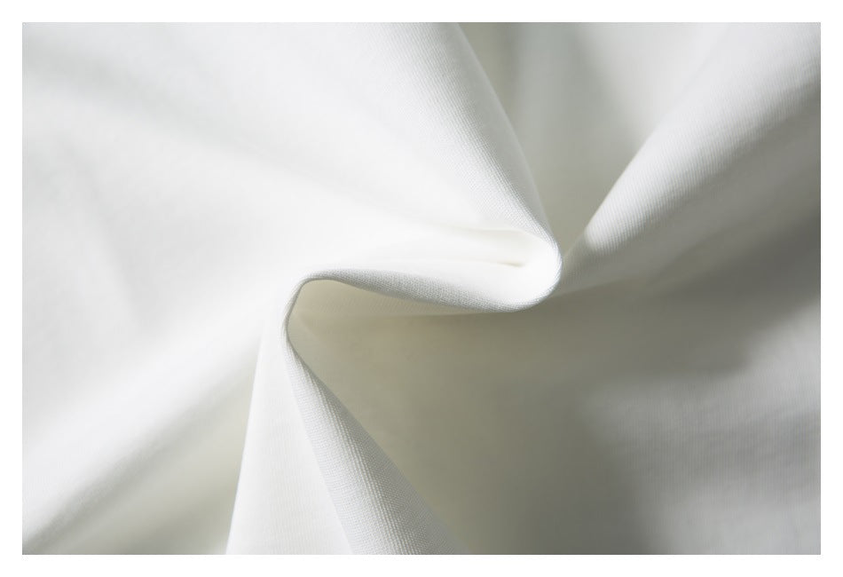 Close-up of white fabric draped in soft folds, showing a fine textured weave.