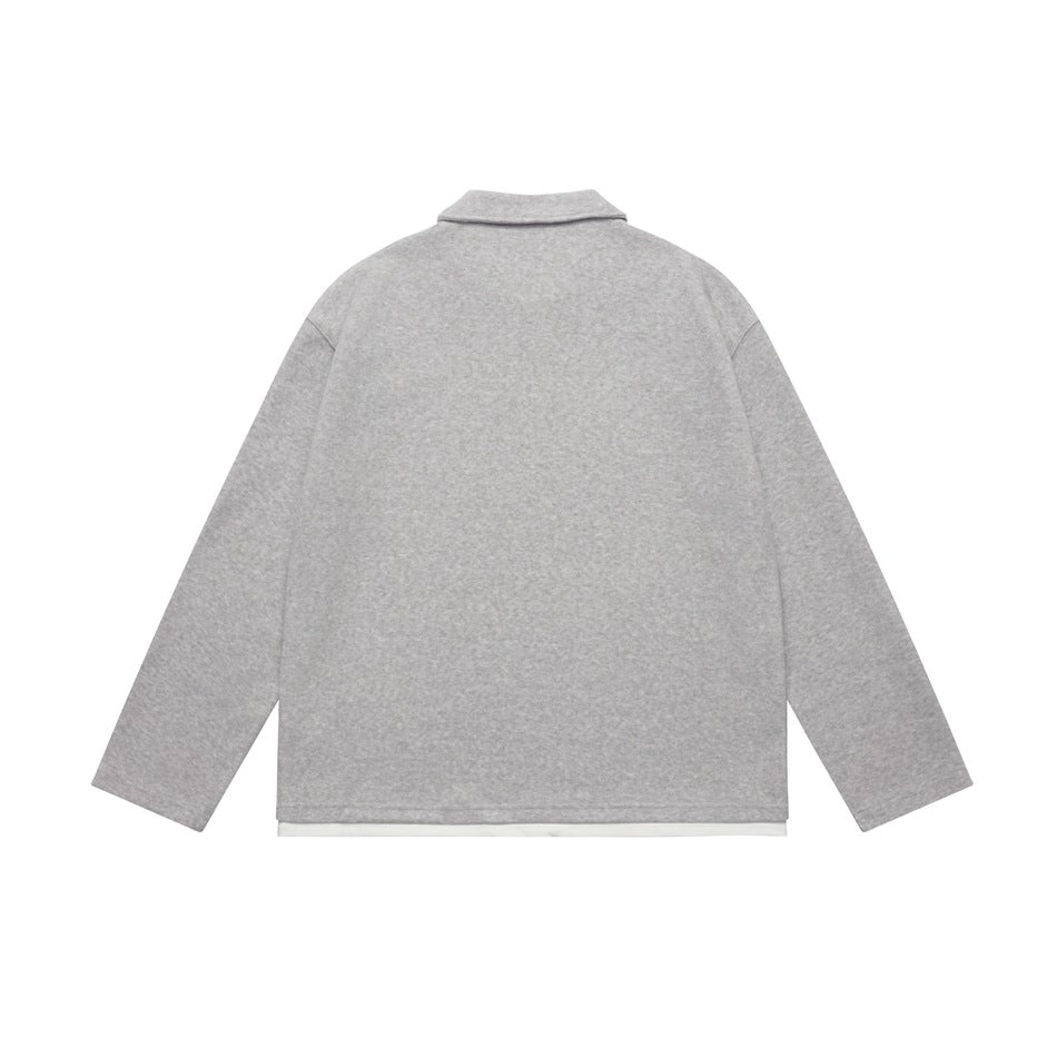 Back view of a light gray long-sleeve collared top with a straight hem and a narrow white layer showing below.