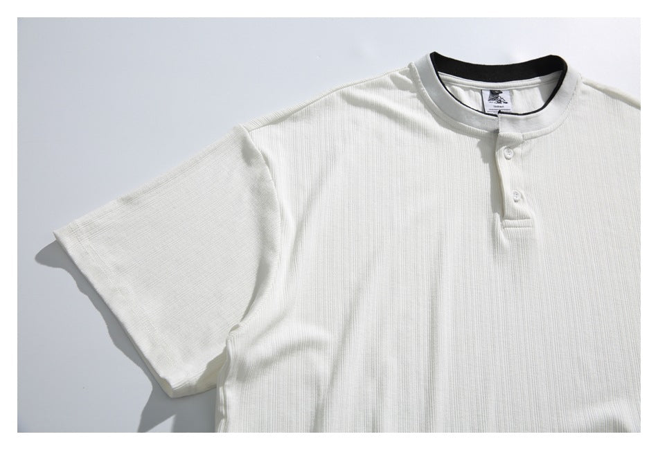 White ribbed short-sleeve henley shirt laid flat, with a black-trimmed collar and two-button placket.