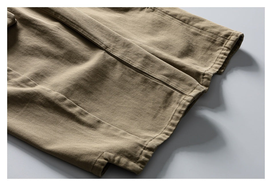 Close-up of tan trouser fabric, seams, and a finished edge laid flat.