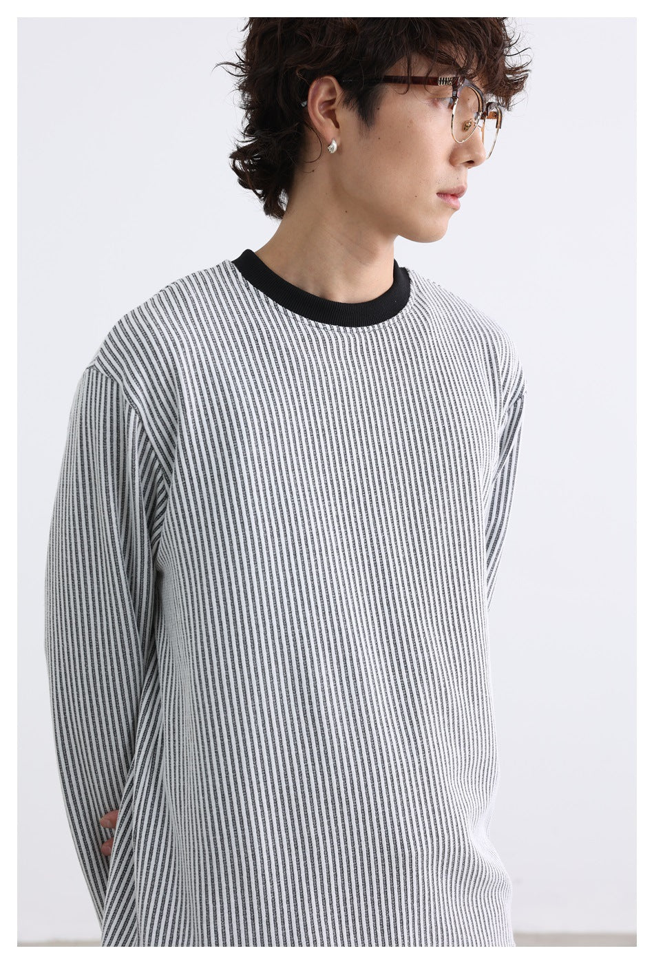 Close-up of a model wearing a gray-white vertical striped crew-neck top with black ribbed collar