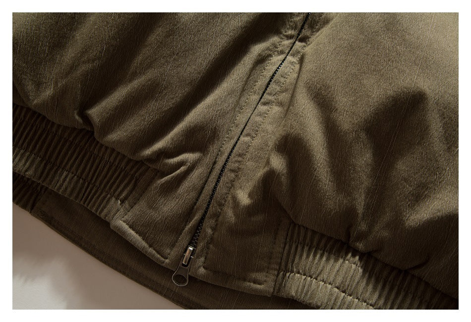 Close-up of an olive-brown jacket's front zipper and gathered lower hem.