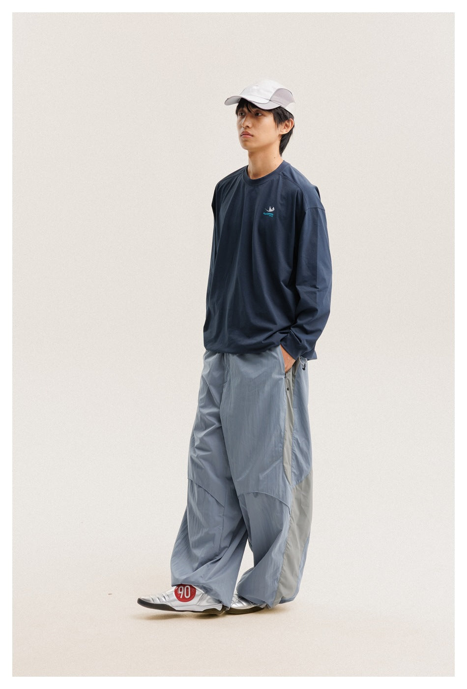 Model in a navy long-sleeve shirt and pale blue wide-leg pants, shown from a three-quarter front angle.