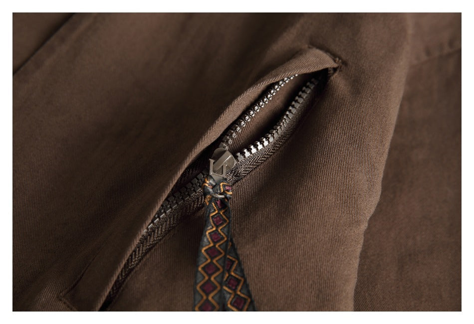 Close-up of a zipper on brown fabric, with a multicolored patterned pull tab.