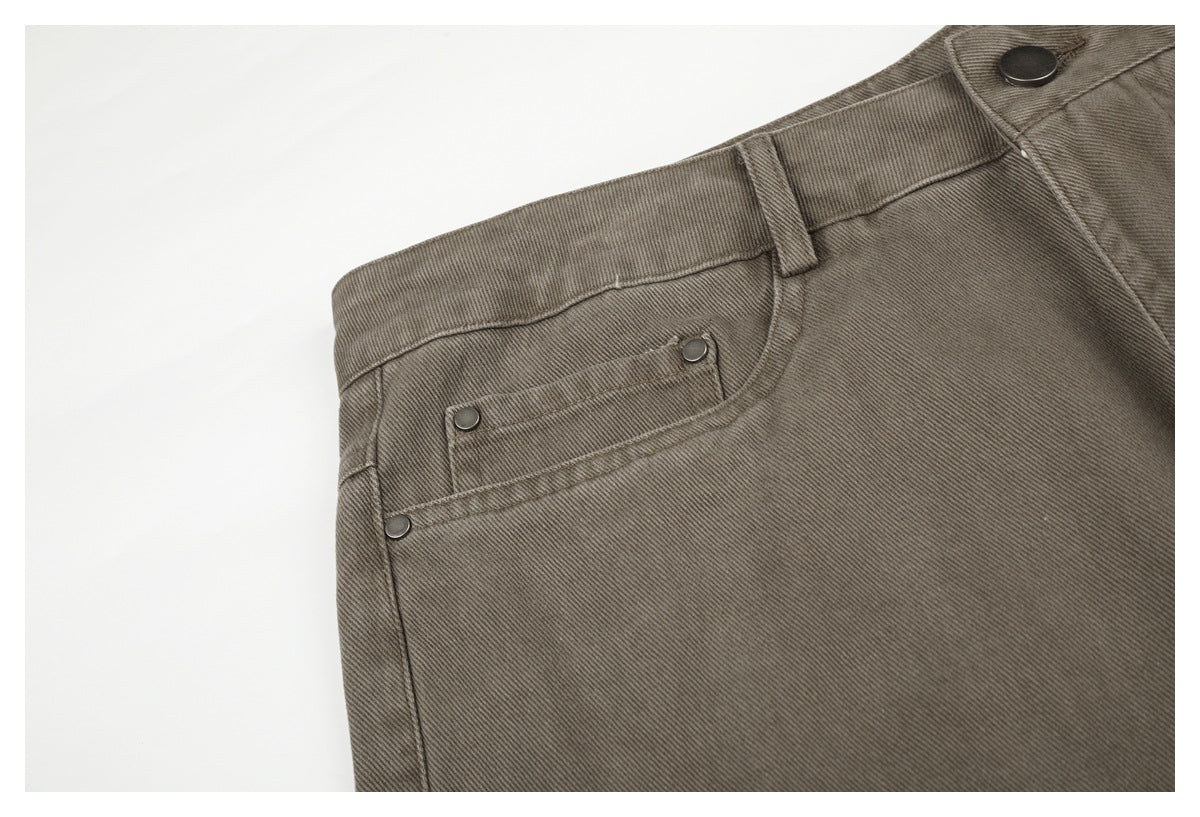 Close-up of a taupe-gray pants front pocket with metal rivets, belt loop, waistband, and button.