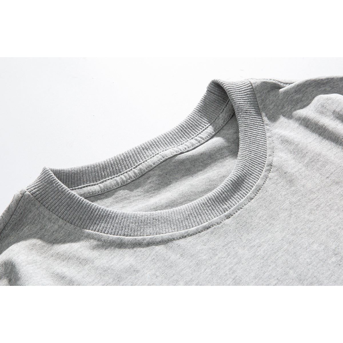 Close-up of a light gray T-shirt's ribbed crew neck and stitching.
