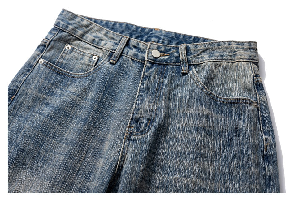 Cropped front view of blue faded jeans showing the waistband, button, fly and front pockets.