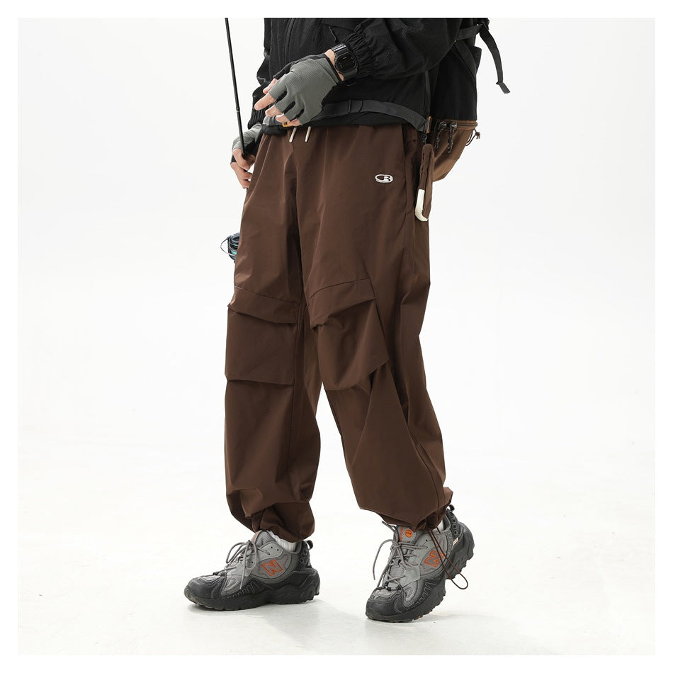 Model wearing loose dark brown cargo pants with layered thigh pockets, shown at a slight angle.
