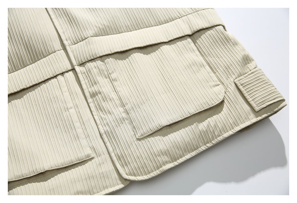 Close-up of an ivory ribbed jacket showing a large flap pocket and adjustable cuff tab.