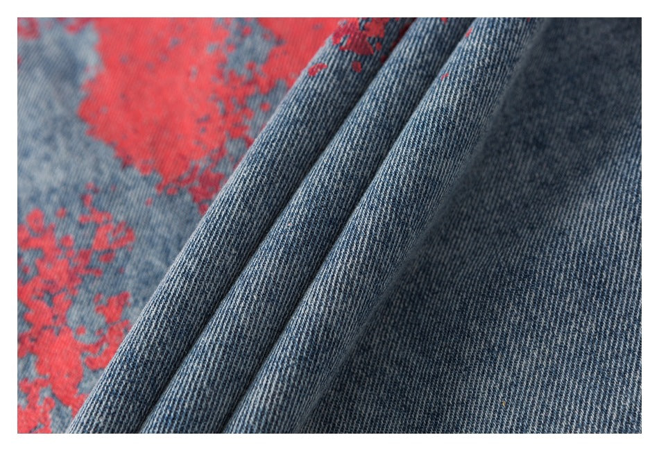 Close-up of folded blue denim fabric showing its weave and distressed red print.