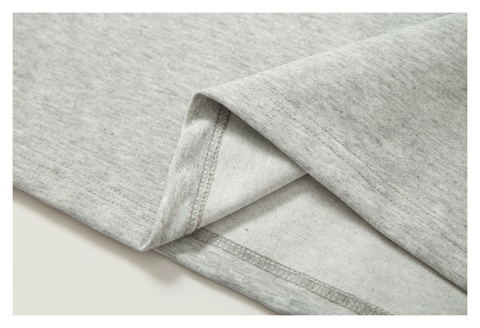 Close-up of a light gray heathered garment hem with visible stitching and folded fabric.