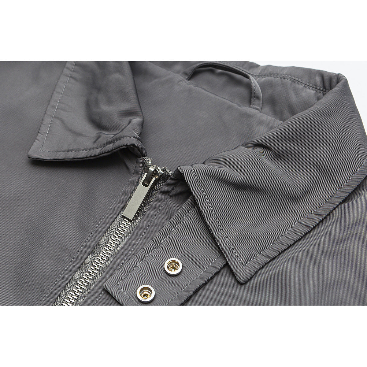 Close-up of a gray jacket collar, silver front zipper and snap-fastened flap.