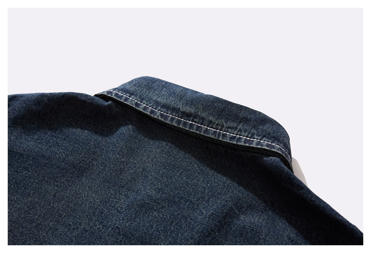 Close-up of a pointed collar on a dark indigo denim shirt with contrast stitching.