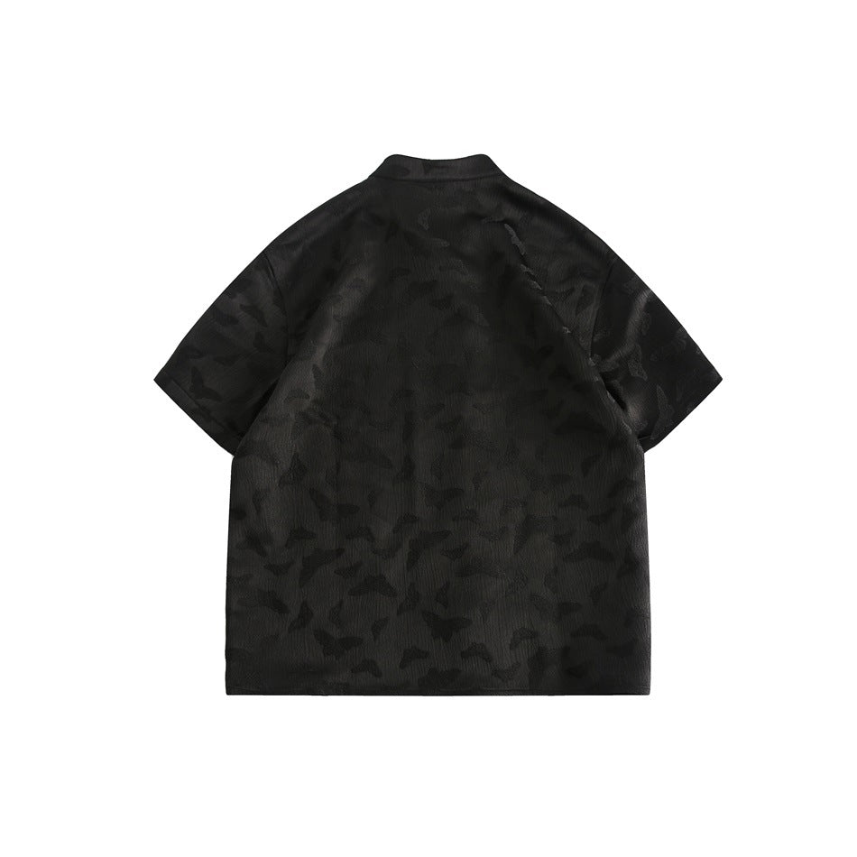 Back view of a black short-sleeve shirt with a stand collar and subtle tonal camouflage-like texture.