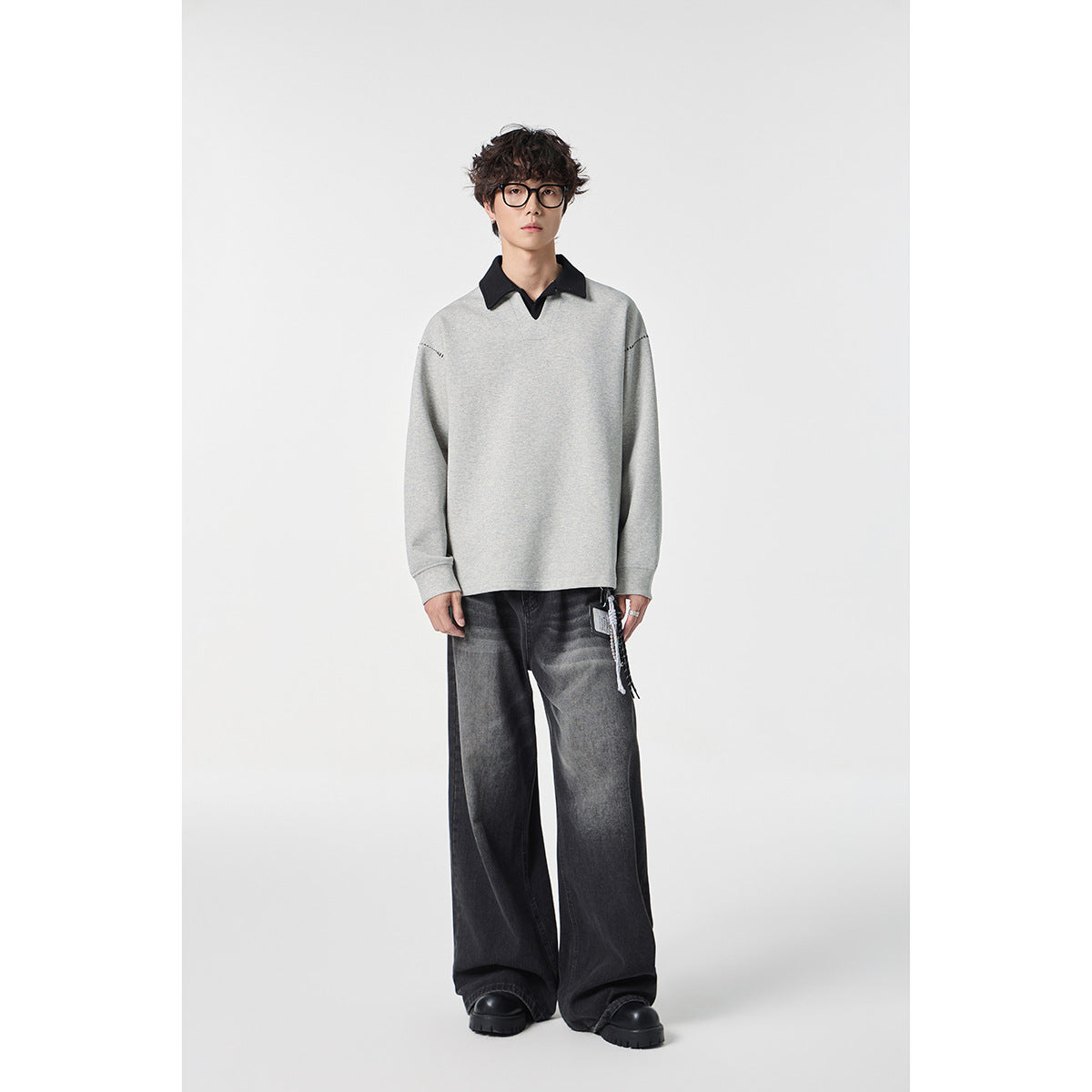 Full-length model wearing a light gray collared top with dark wide-leg jeans and black shoes.