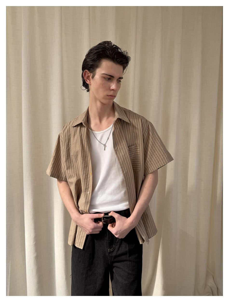 Closer front view of a model wearing an open tan striped short-sleeve shirt over a white tee.