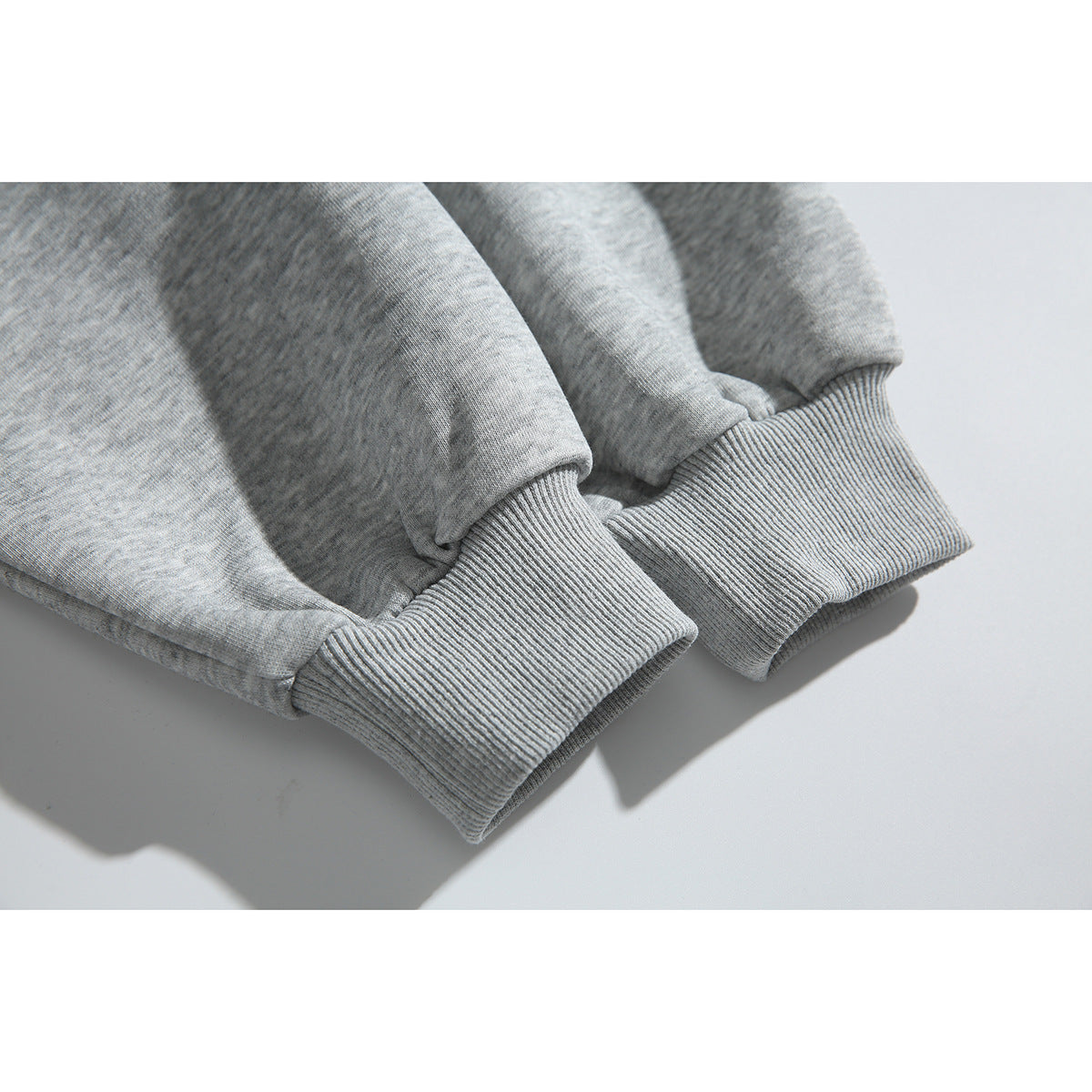 Close-up of the ribbed cuffs and sleeves of a heather-gray sweatshirt.
