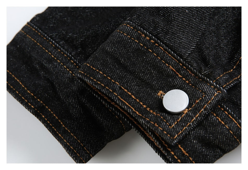 Close-up of a black denim cuff tab with orange stitching and a silver snap button.