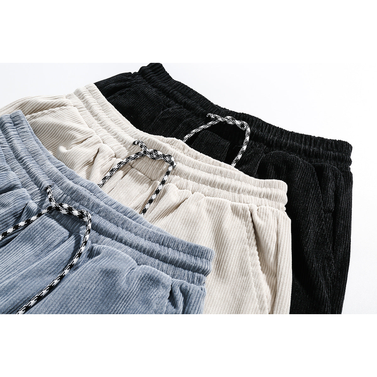 Close-up of black, cream, and light blue corduroy shorts with elastic waistbands and patterned drawstrings.